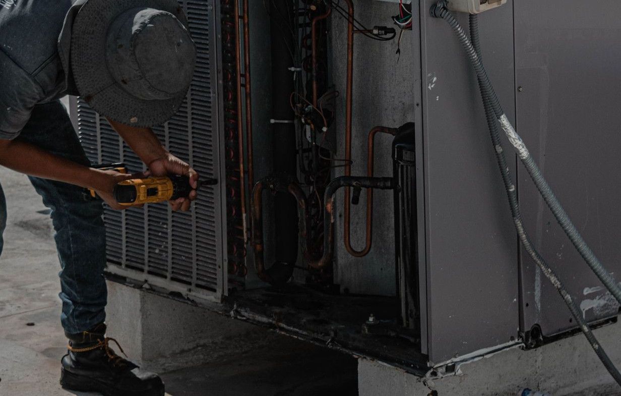 A technician is repairing an air conditioning unit on a rooftop, demonstrating skilled manual work.